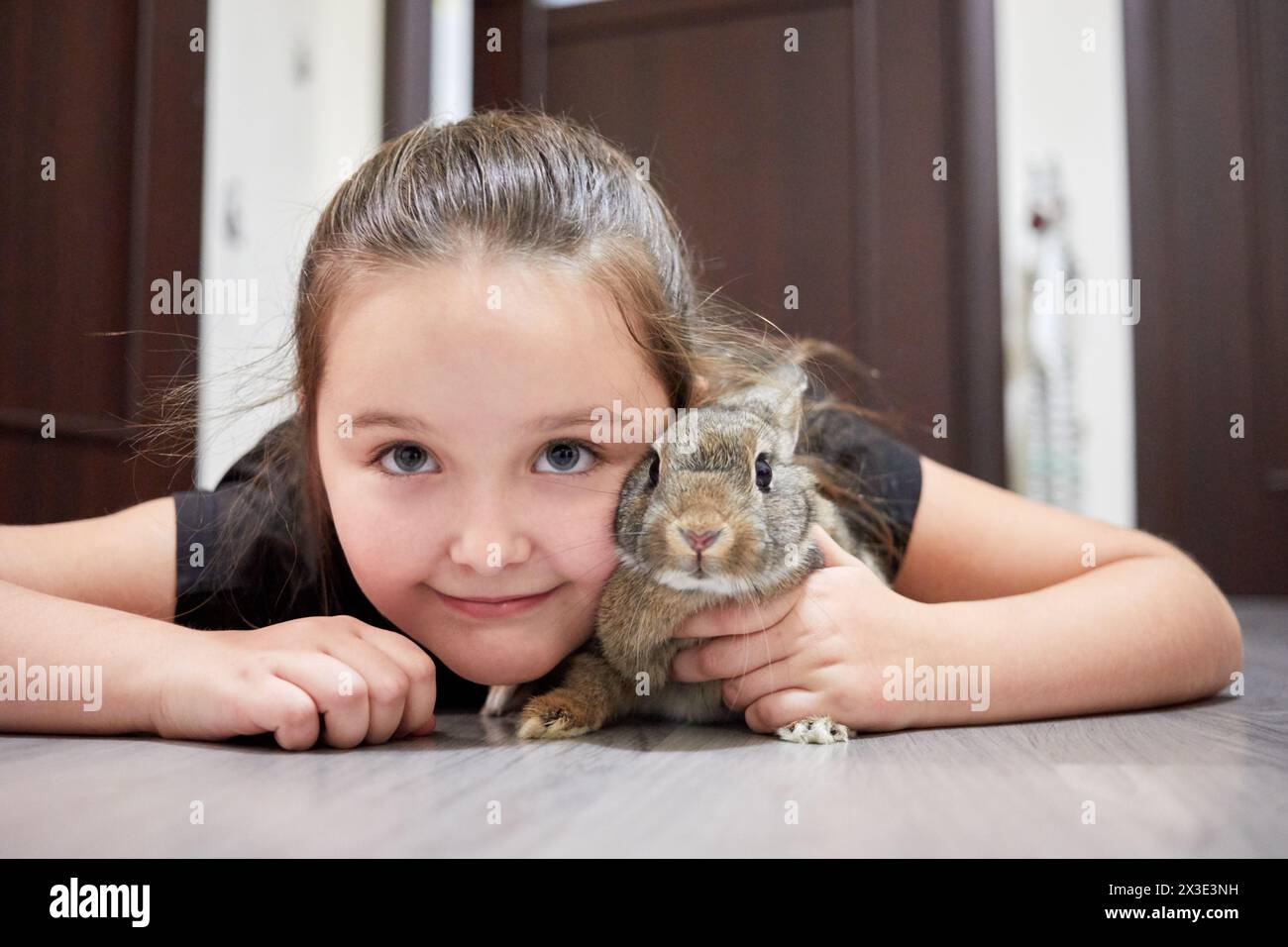 Petite fille se trouve avec lapin sur le sol dans l'appartement. Banque D'Images