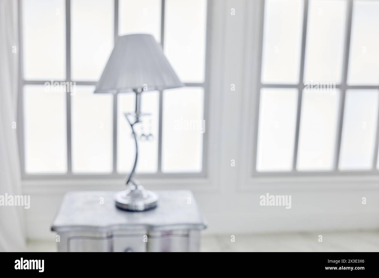 Lampe de table sur la table de chevet contre la fenêtre en treillis dans la chambre, image floue. Banque D'Images