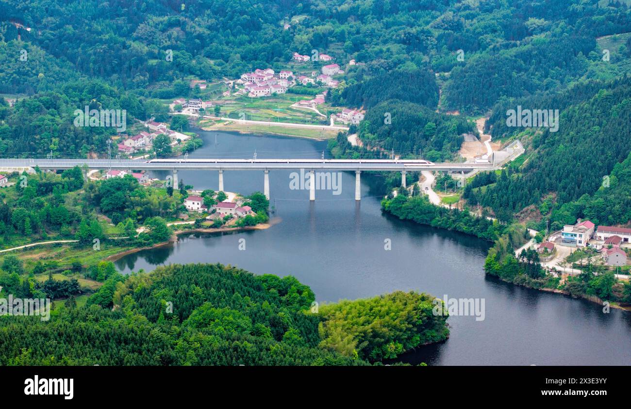 Hefei. 26 avril 2024. Une photo de drone aérien montre un train circulant sur le pont Jianhe le long de la ligne de chemin de fer Chizhou-Huangshan dans la province d'Anhui, dans l'est de la Chine, le 26 avril 2024. Le chemin de fer Chizhou-Huangshan, reliant la ville de Chizhou et la ville de Huangshan, dans la province d'Anhui, dans l'est de la Chine, a commencé à fonctionner vendredi. Il s'agit d'une route touristique reliant la montagne Jiuhua, la montagne Huangshan, le lac Taiping et d'autres attractions touristiques, ce qui est d'une grande importance pour la promotion du développement économique et social le long de la route. Crédit : Liu Yucai/Xinhua/Alamy Live News Banque D'Images