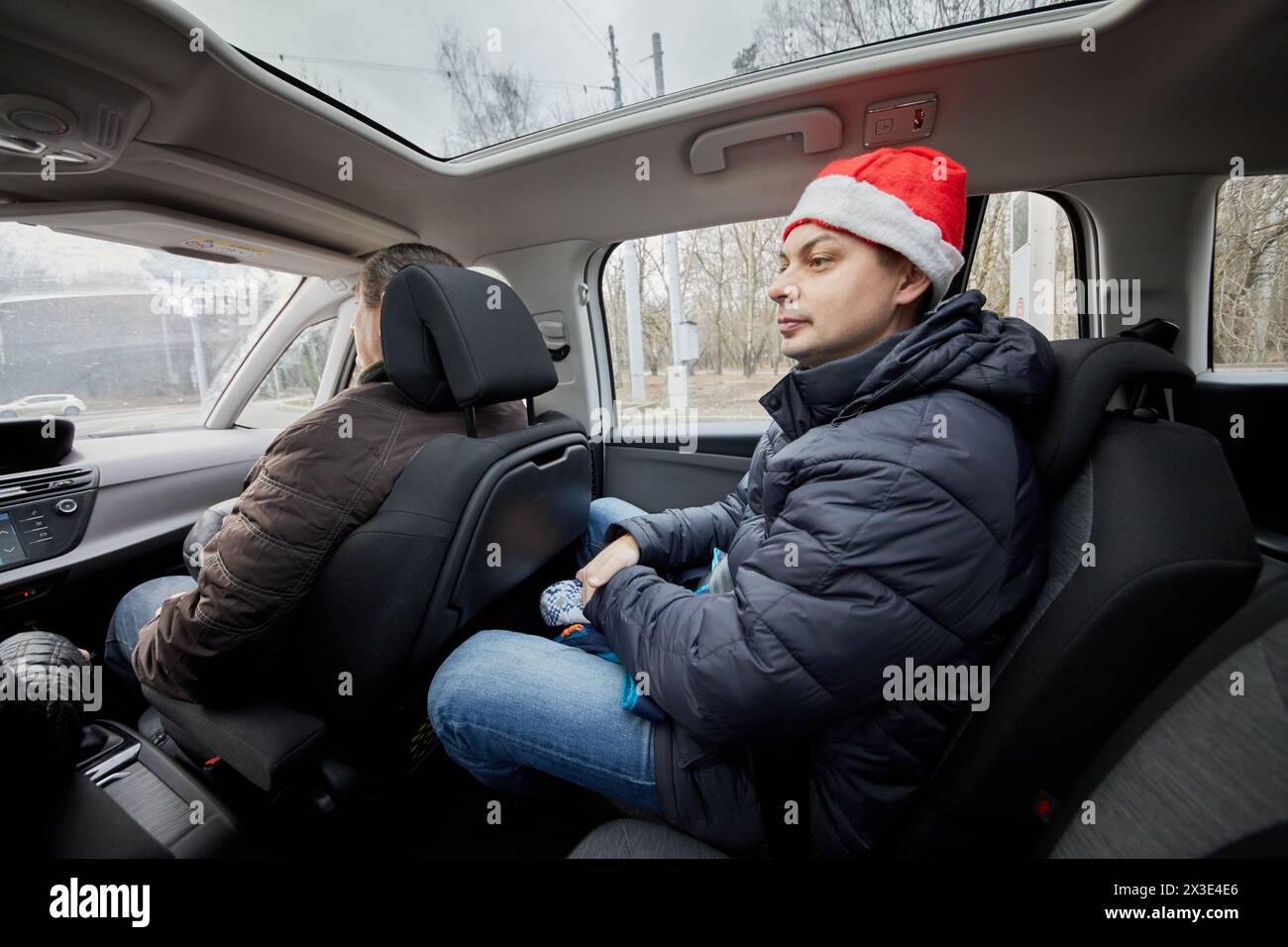 Homme dans le chapeau de Père Noël sur le siège passager dans la voiture. Banque D'Images