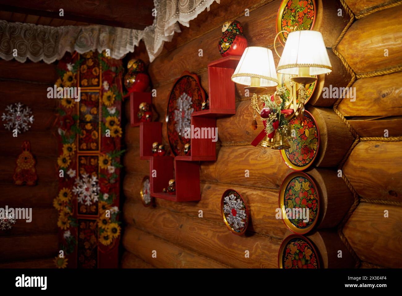 Mur de bûches de bois dans le chalet décoré avec des plats peints dans le style folklorique Khokhloma et des flocons de neige artificiels. Banque D'Images