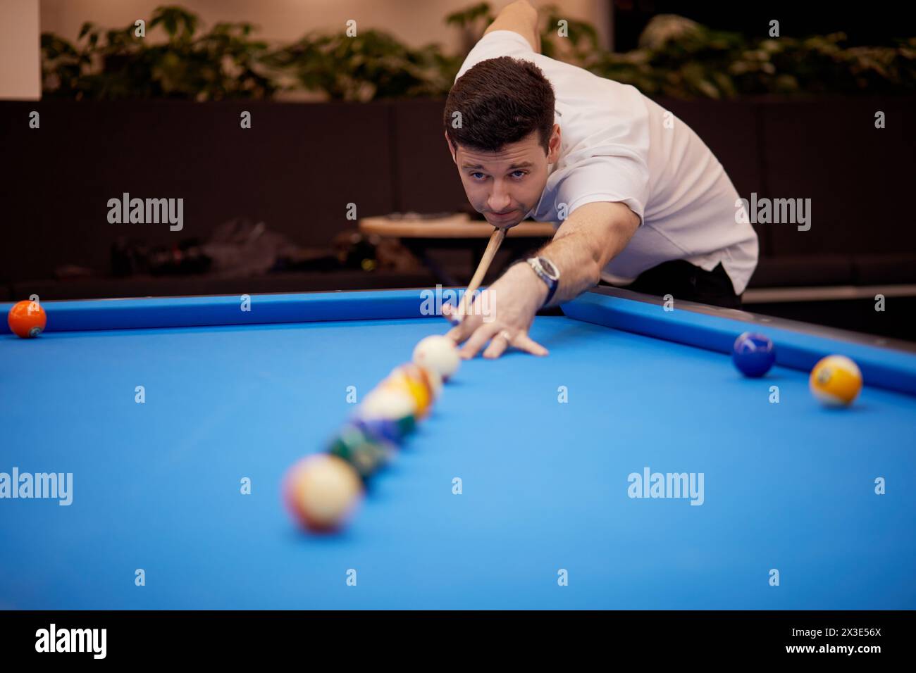 Homme en polo-col blanc joue au billard club. Banque D'Images