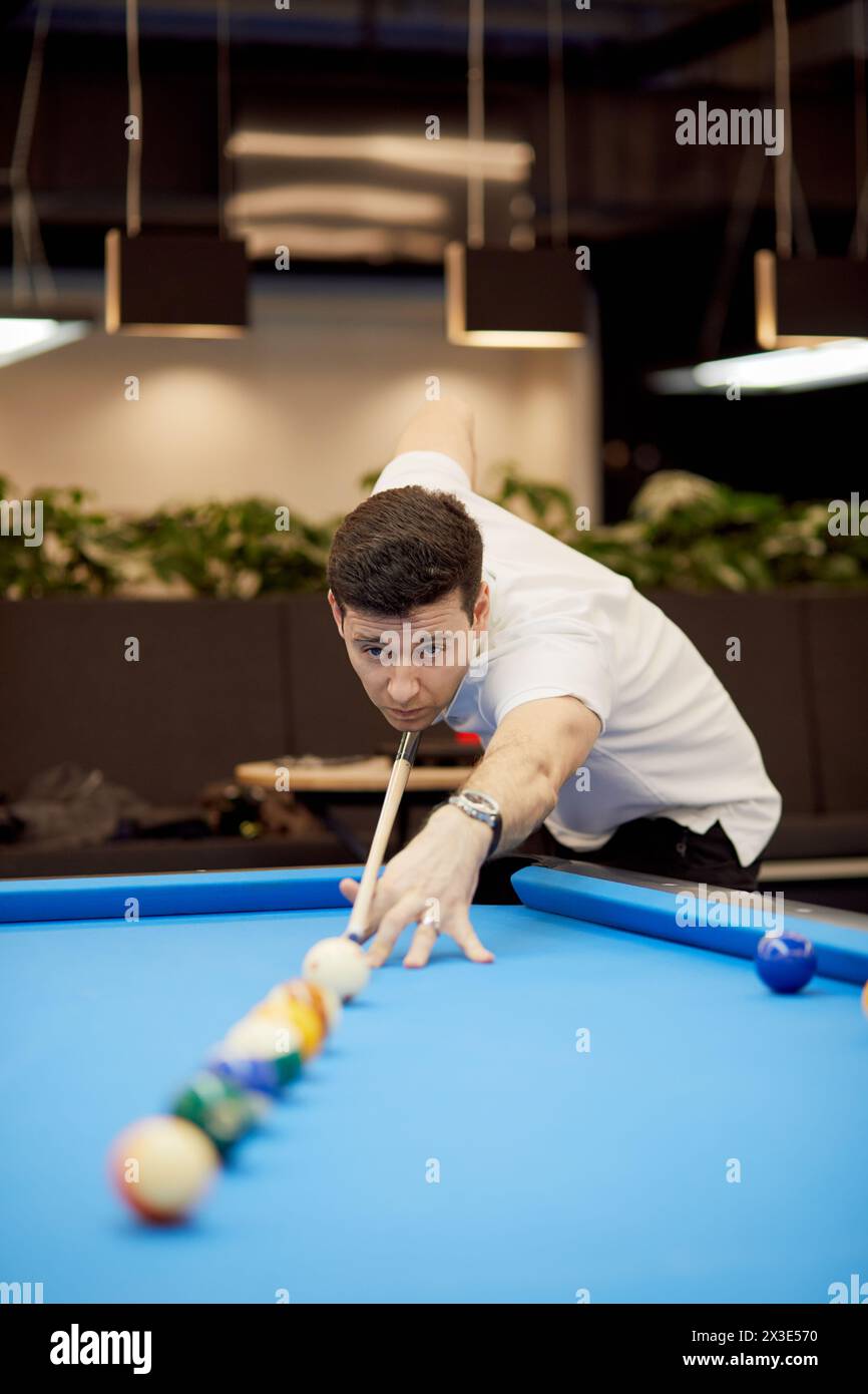 Homme en polo-col blanc joue au billard dans le club. Banque D'Images