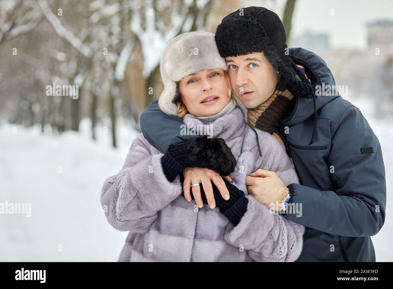 Homme et femme se tiennent embrassant sur l'allée dans le parc d'hiver. Banque D'Images