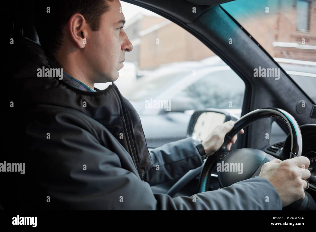 Sièges d'homme sur le siège du conducteur au volant dans la voiture moderne le jour d'hiver, vue de profil. Banque D'Images