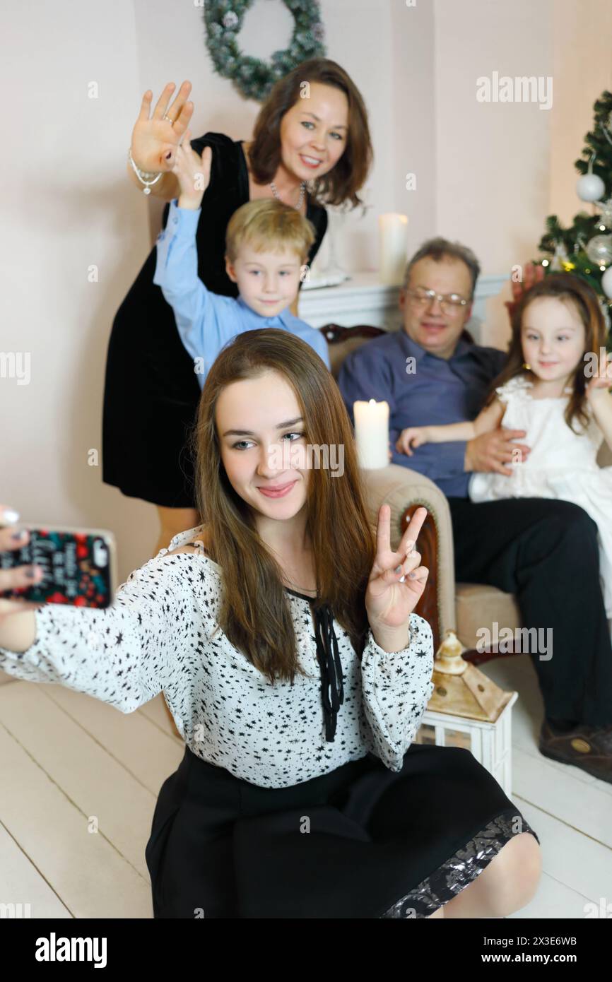 Fille avec des bretelles selfies avec père, mère, sœur, frère près de l'arbre de noël, se concentrer sur l'adolescent Banque D'Images