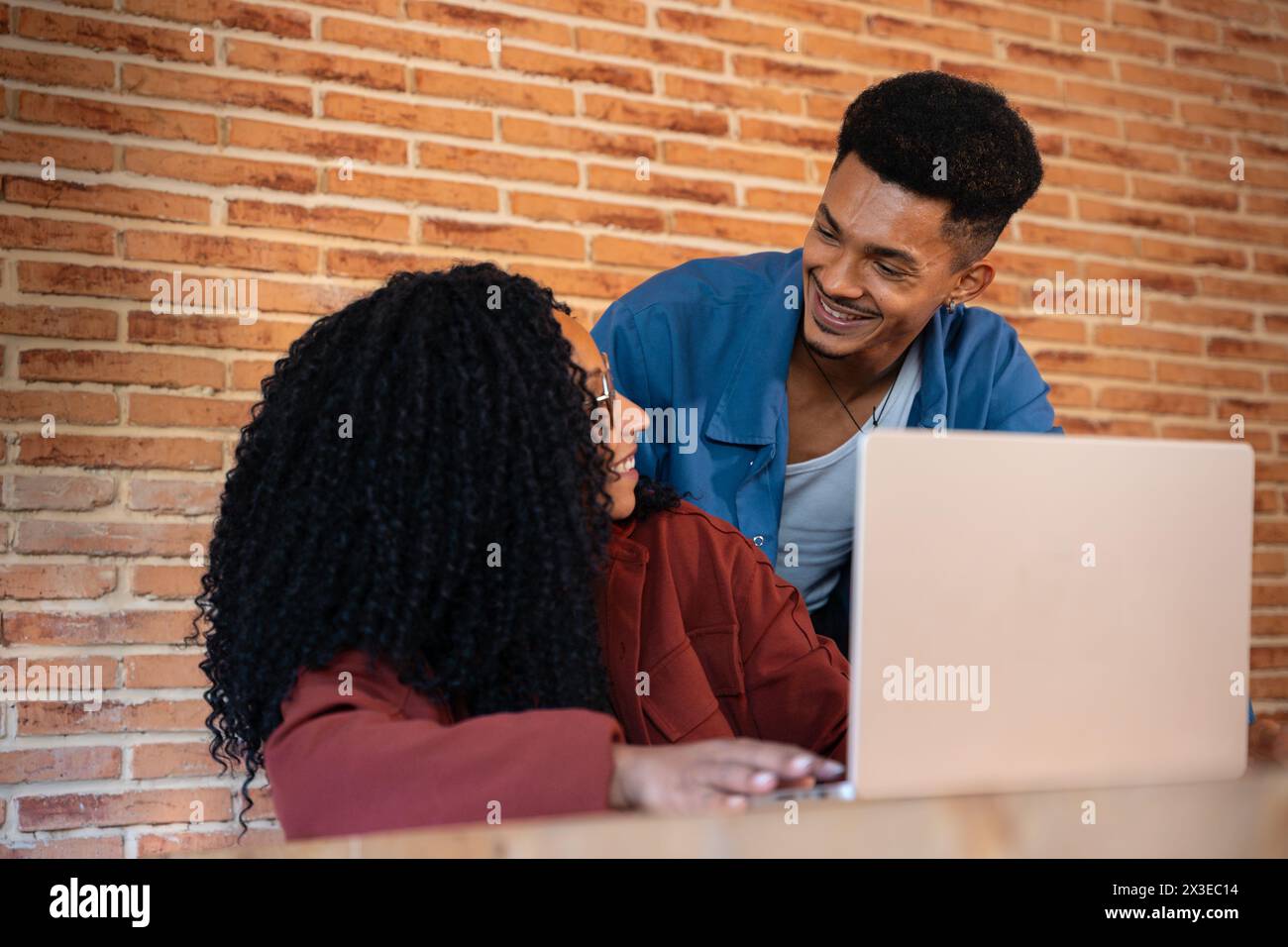 Heureux homme multiethnique et femme conversent et surfent sur Internet sur un ordinateur portable à l'intérieur. Banque D'Images