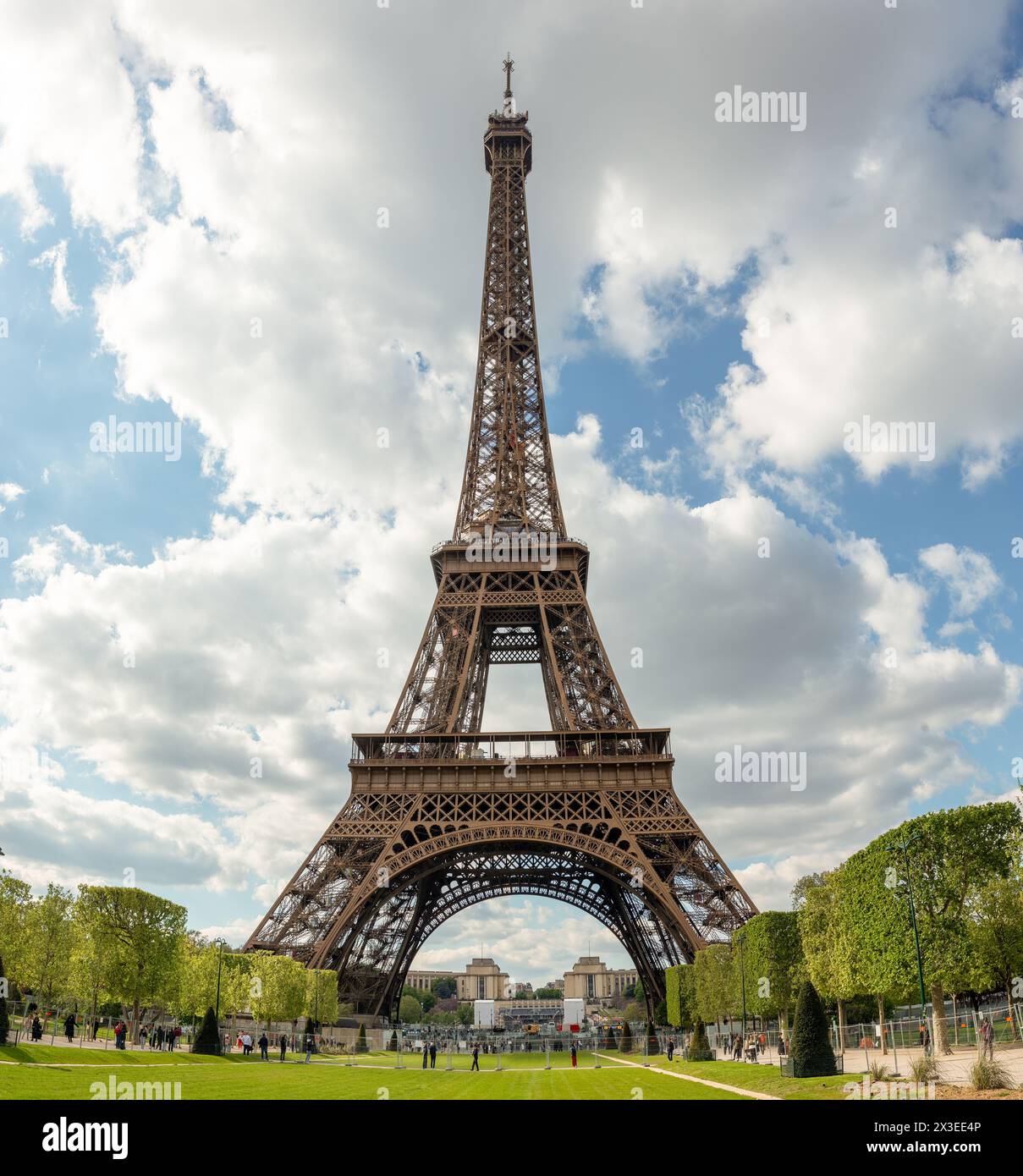 Embrassant les caprices du printemps, la Tour Eiffel se dresse avec un ciel partiellement nuageux en toile de fond, enchantant les visiteurs par son allure intemporelle. Banque D'Images