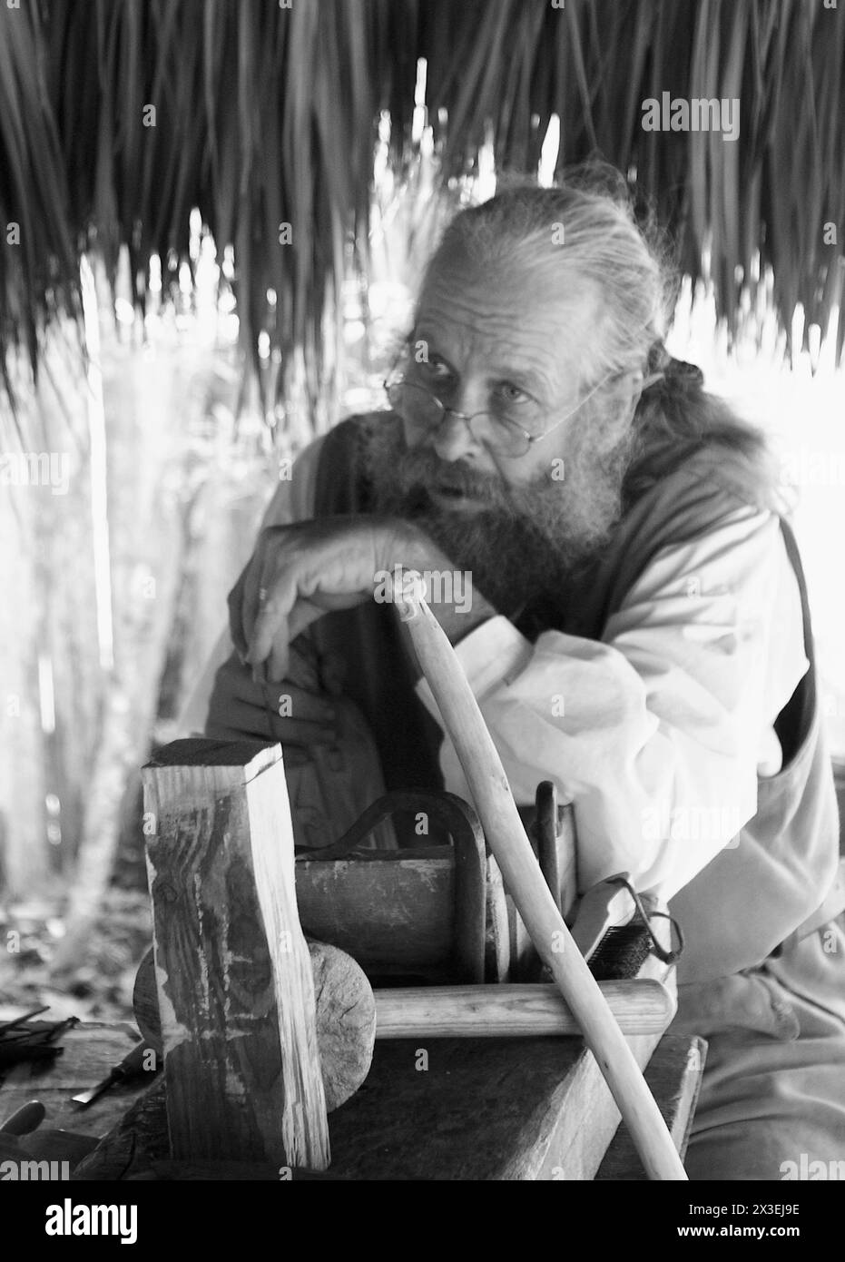 Un homme en tenue coloniale sculpte une statue dans du bois à Saint Augustine, Floride, USA. Cet artisanat traditionnel démontre des techniques artisanales historiques. Banque D'Images