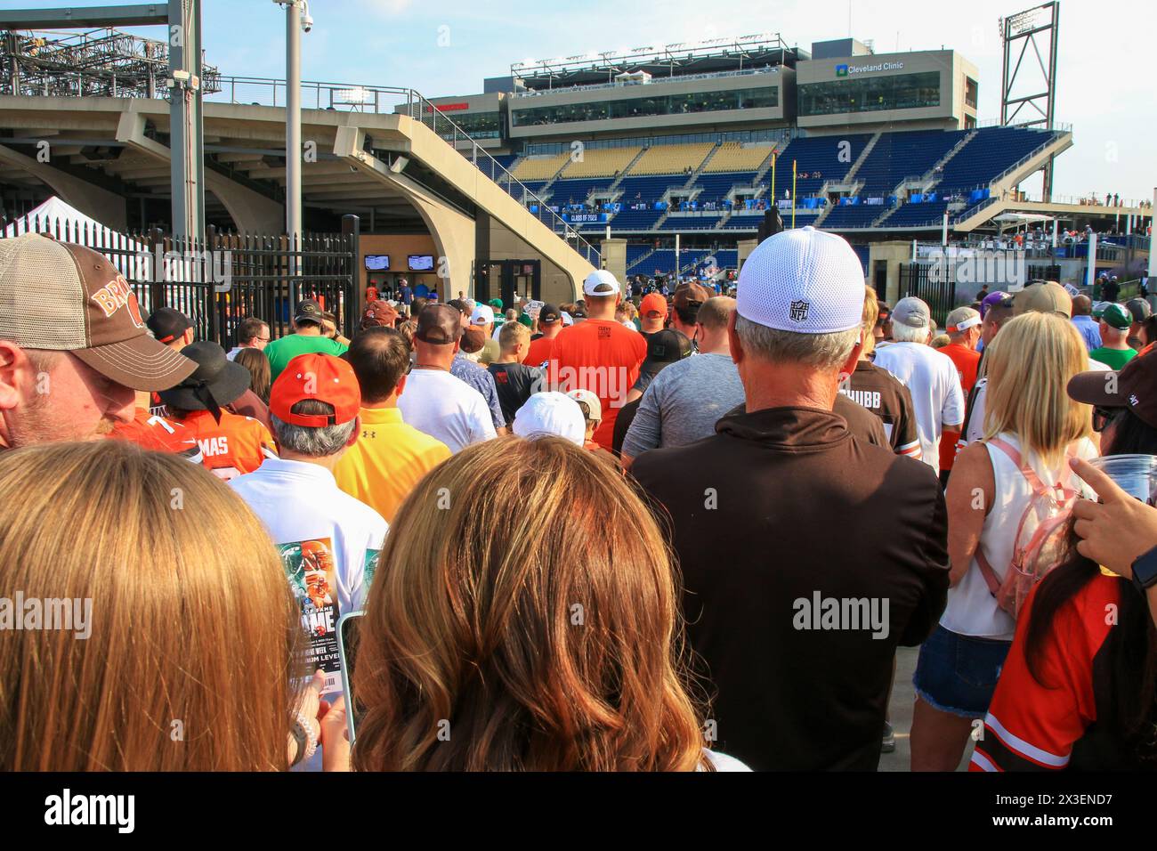 Canton, Ohio, États-Unis - 3 août 2023 : un groupe de personnes diverses debout devant un grand stade, certains discutant, d'autres prenant des photos. Banque D'Images