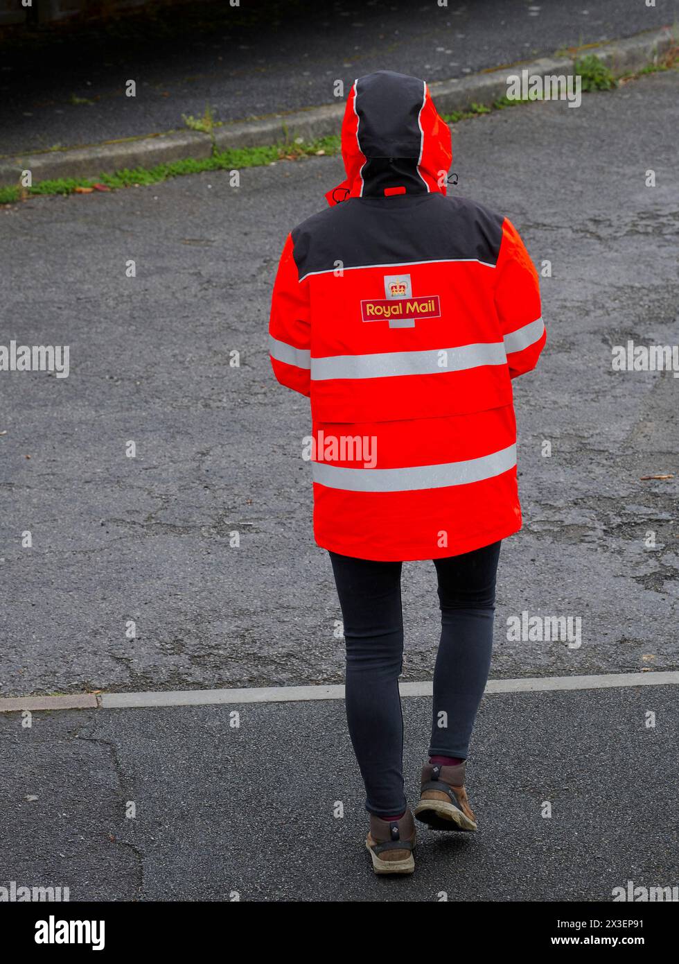 Livreur de Royal mail dans une veste rouge vif avec sweat à capuche un jour de pluie. Banque D'Images