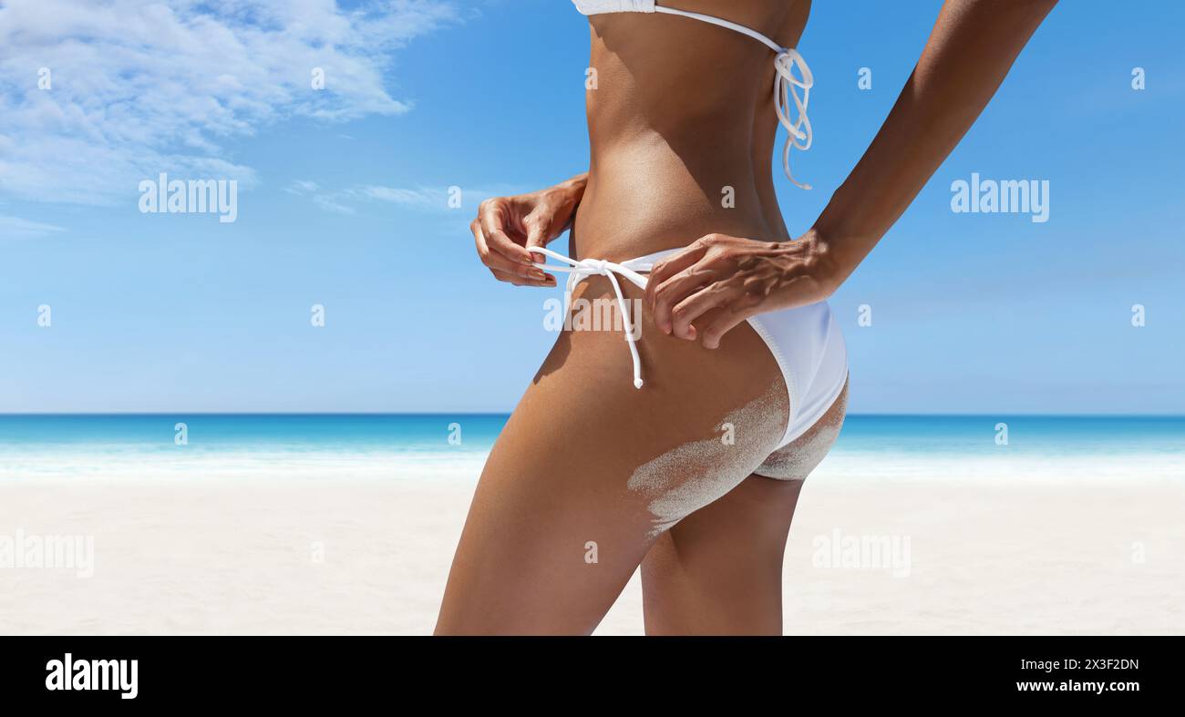 Vacances d'été chaudes, femme sur la plage portant un bikini avec du sable sur ses fesses. Sur fond panoramique de bord de mer. Concept de shoppin en ligne Banque D'Images
