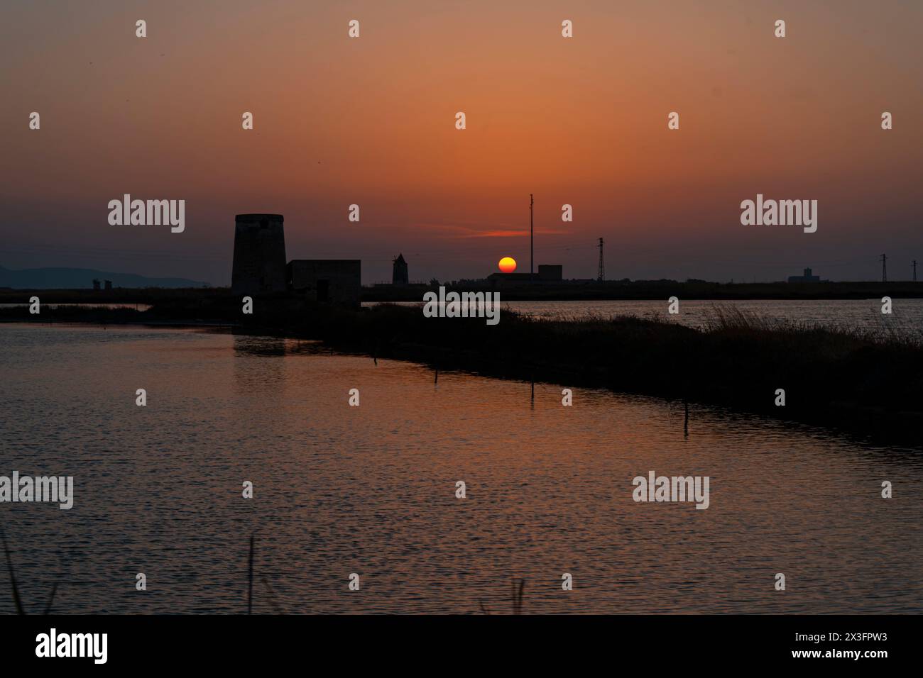 Vieux moulin à vent à Saline di Trapani e Paceco au coucher du soleil, Sicile. Banque D'Images
