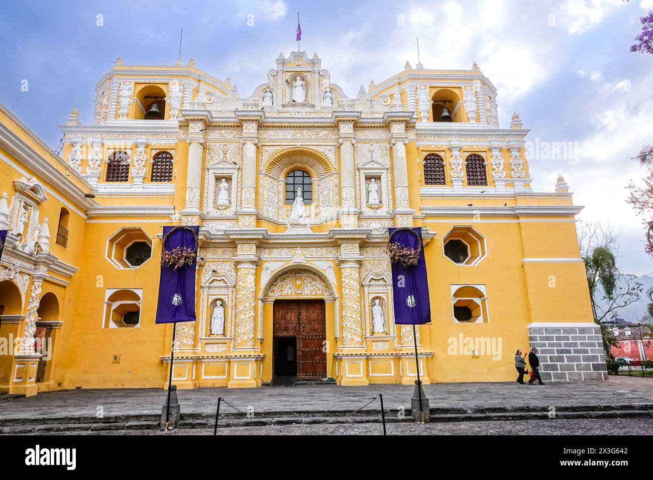 Façade extérieure de l'église et couvent de la Merced, une église catholique ornée construite dans le style Churrigueresque en 1749 à Antigua, Guatemala. Le bâtiment orné d'un jaune vif présente des détails en relief dans des motifs arabesques appelés stucco ataurique. Banque D'Images