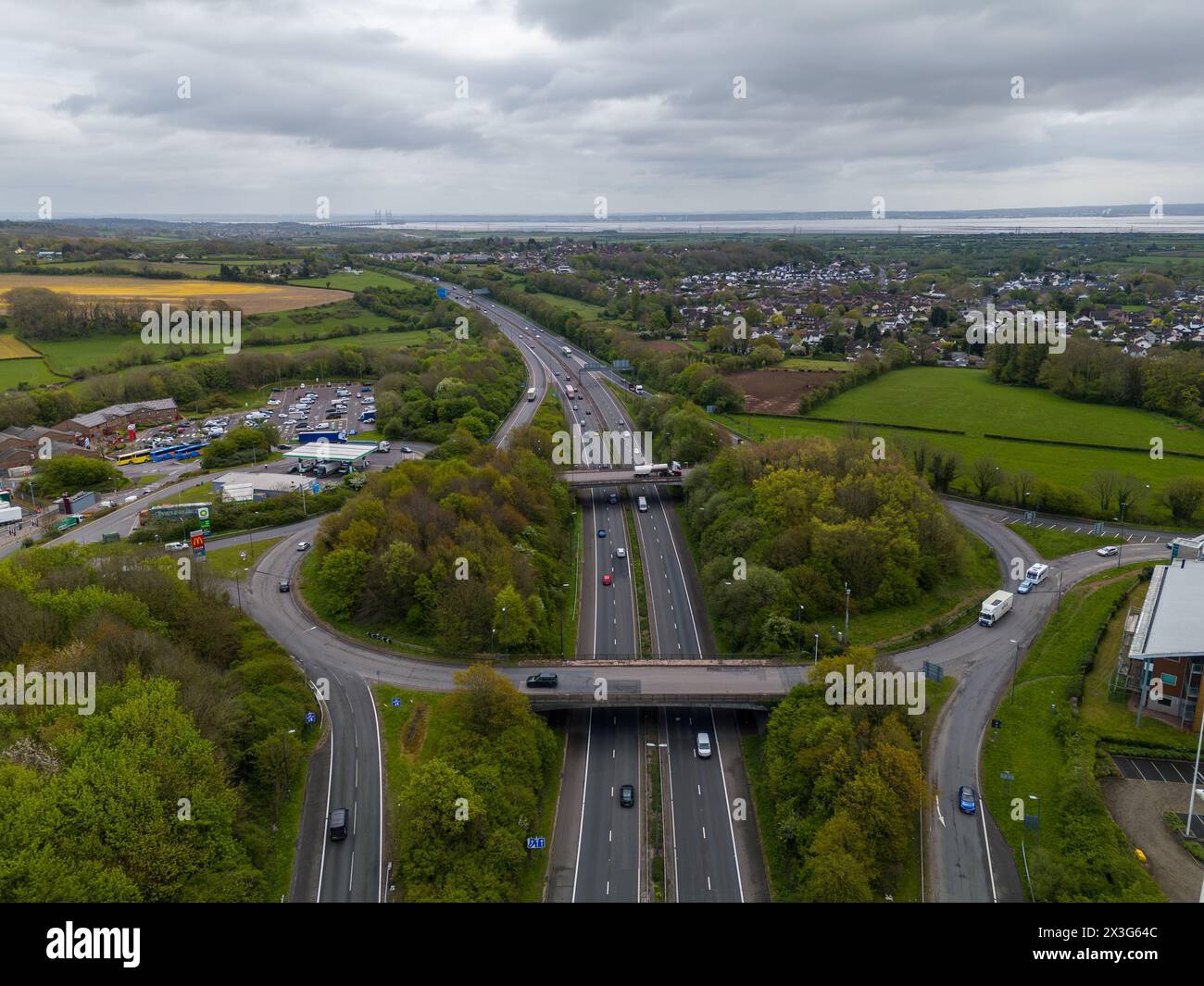 Prise de vue par drone capturant un carrefour d'autoroute fréquenté avec des champs verdoyants et des banlieues urbaines Banque D'Images