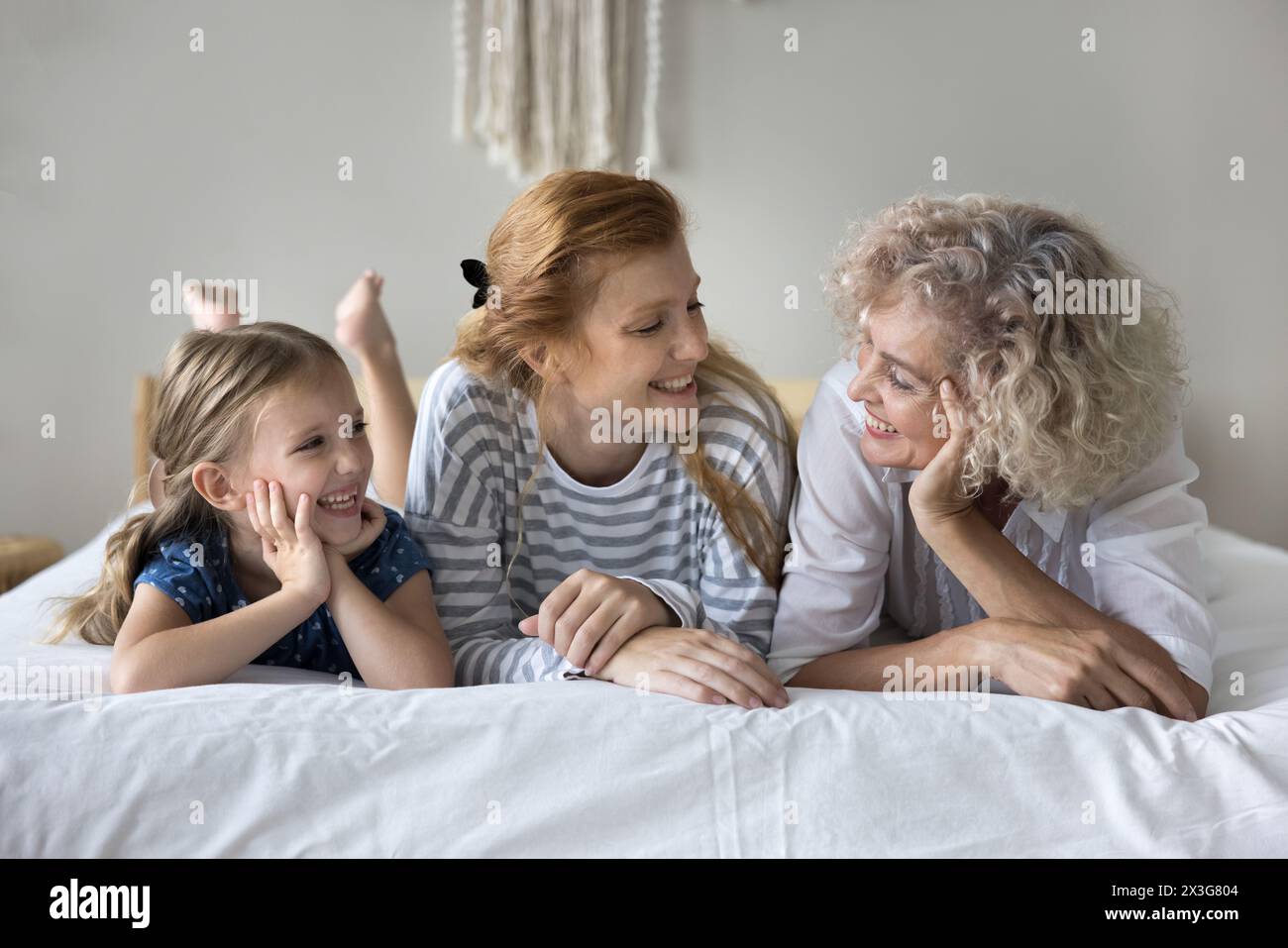 Fille couchée sur le lit avec la jeune mère et la mamie aimante Banque D'Images