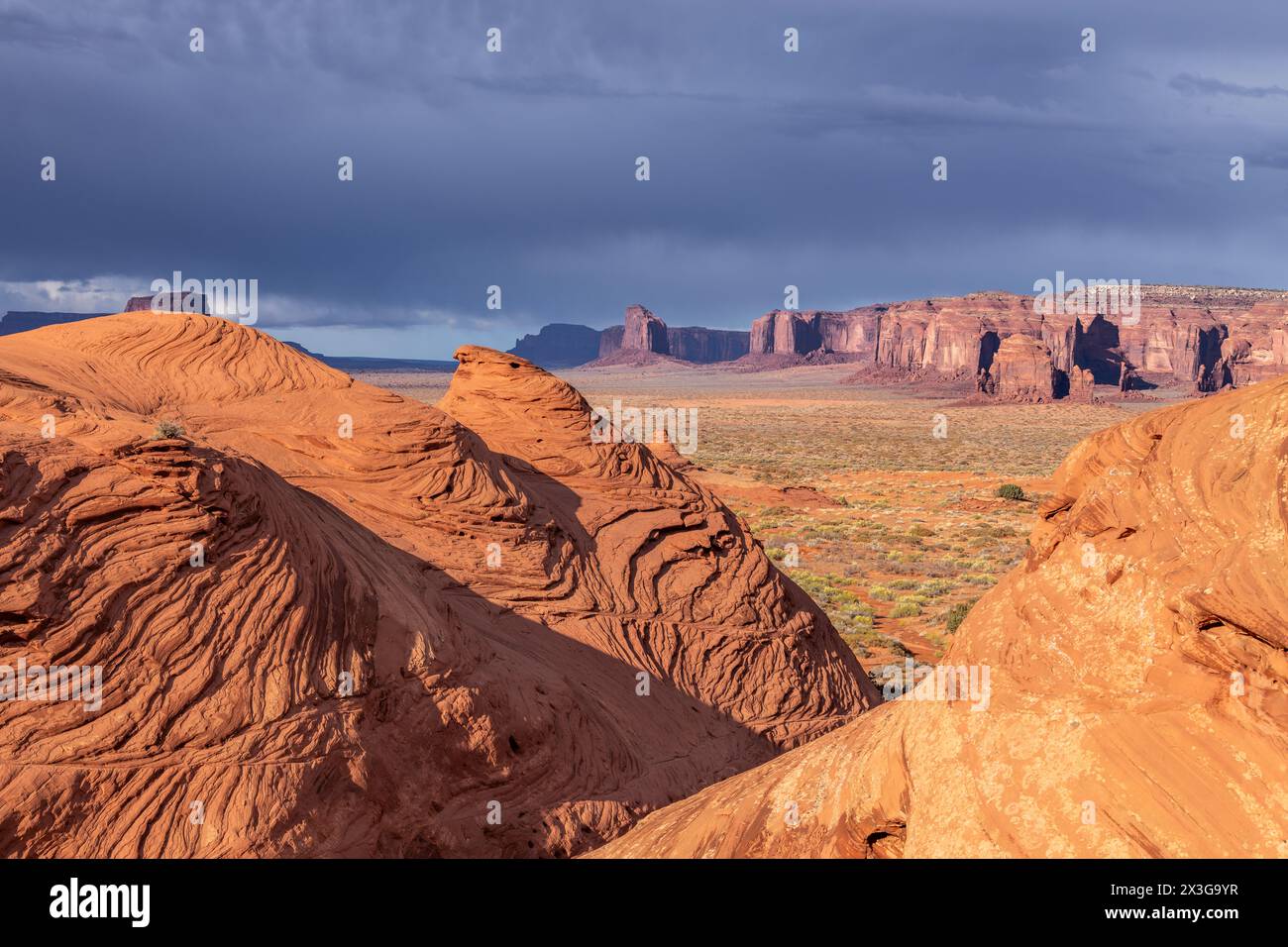 Une randonnée dans une zone reculée de Monument Valley Arizona au crépuscule montre une belle étendue encadrée par des modèles d'érosion qui se sont formés dans le sandston Banque D'Images
