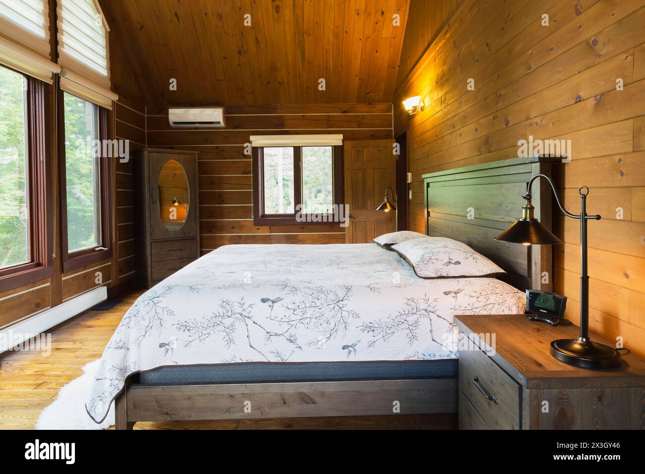 Lit king size sur cadre en bois avec tête de lit en bois, table de nuit avec lampe de style industriel antique, commode avec miroir ovale dans la chambre principale à l'intérieur d'un Banque D'Images