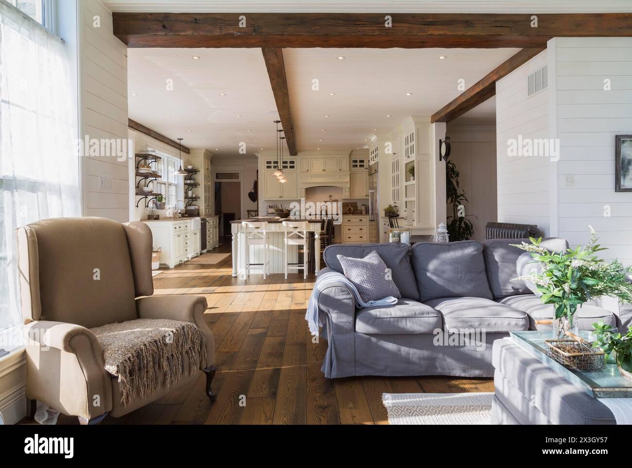 Canapé modèle ektorp rembourré gris foncé, fauteuil bergère dans le salon avec tapis et parquet en bois de chêne teinté à l'intérieur de la maison de style campagnard, Québec Banque D'Images