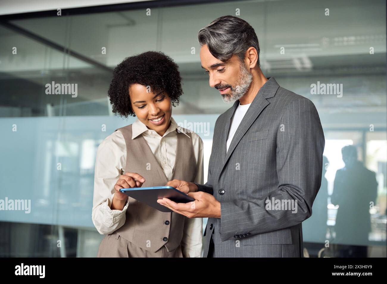 Deux partenaires commerciaux professionnels heureux et diversifiés travaillant au bureau avec tablette. Banque D'Images