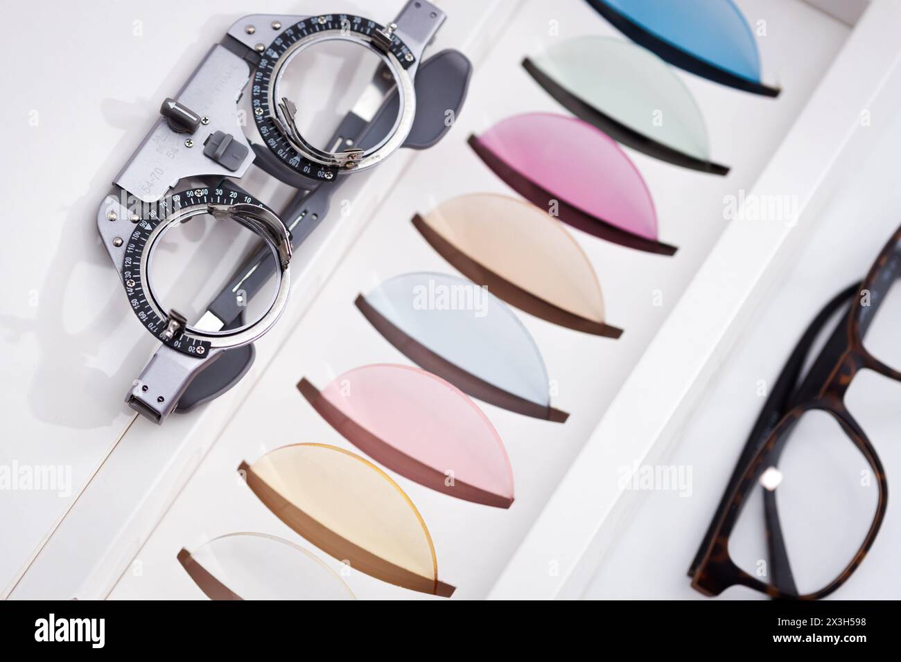 Monture de lunettes de vision avec cadre de test oculaire près de nombreuses lentilles ophtalmologiques colorées pour la protection des yeux Banque D'Images