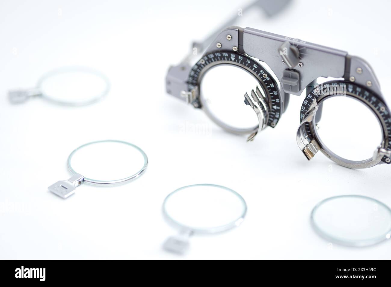 Gros plan de monture de test oculaire pour opticien avec de nombreuses lentilles d'essai différentes pour la protection oculaire sur fond blanc Banque D'Images
