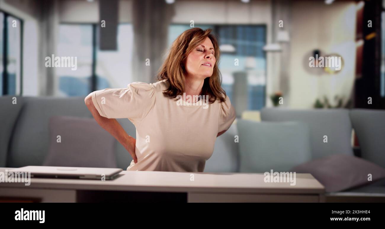 Jeune femme assise sur le canapé ayant mal au dos Banque D'Images