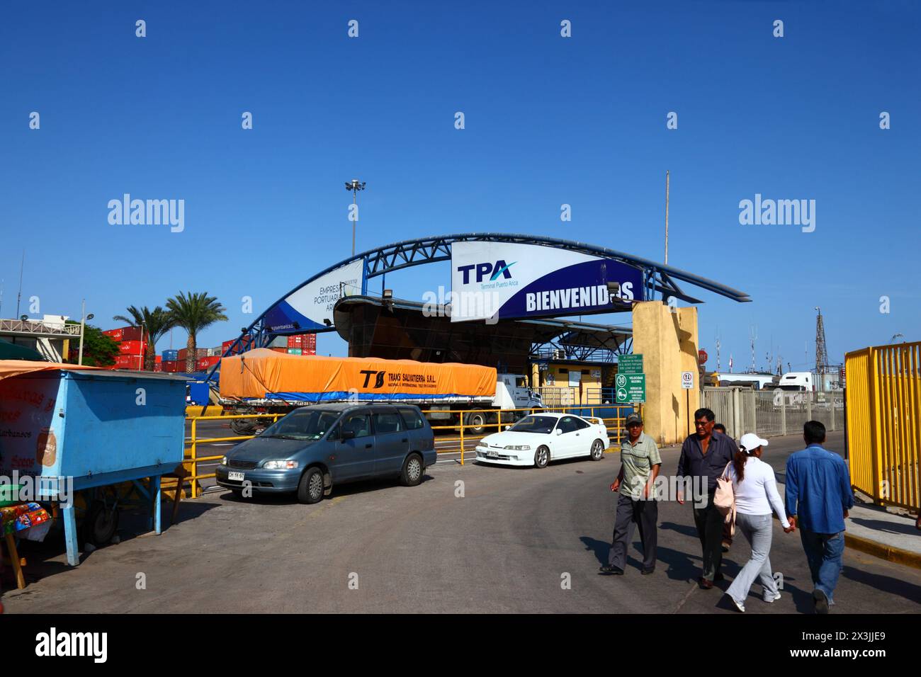 Voitures garées à côté de l'accès à la zone du port de pêche, camion entrant dans le terminal du port commercial en arrière-plan, Arica, Chili Banque D'Images