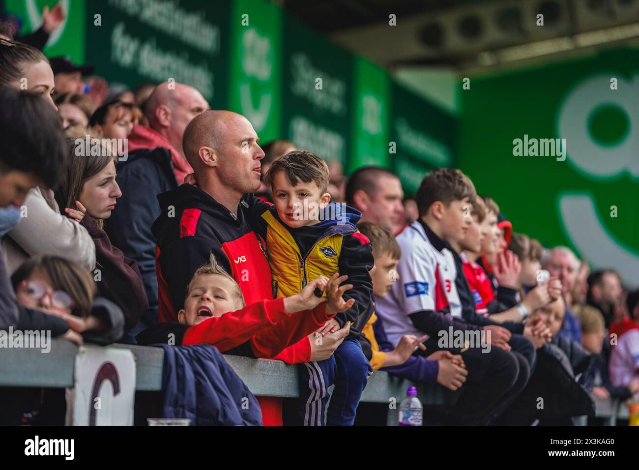 Salford, Manchester, Royaume-Uni. 27 avril 2024. Super League Rugby : Salford Red Devils vs Warrington Wolves au Salford Community Stadium. Un jeune fan de Salford avec son père dans la foule. Crédit James Giblin/Alamy Live News. Banque D'Images