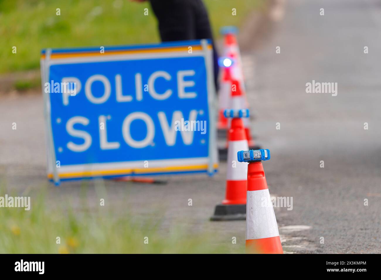 Un signe lent de police avec des lumières LED placées sur des cônes utilisés comme un bloc routier lors d'un incident de police à proximité à Swillington, Leeds, West Yorkshire, Royaume-Uni Banque D'Images