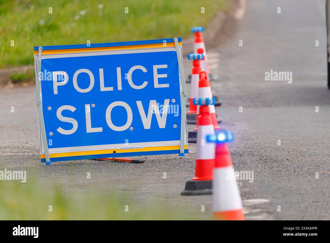 Un signe lent de police avec des lumières LED placées sur des cônes utilisés comme un bloc routier lors d'un incident de police à proximité à Swillington, Leeds, West Yorkshire, Royaume-Uni Banque D'Images
