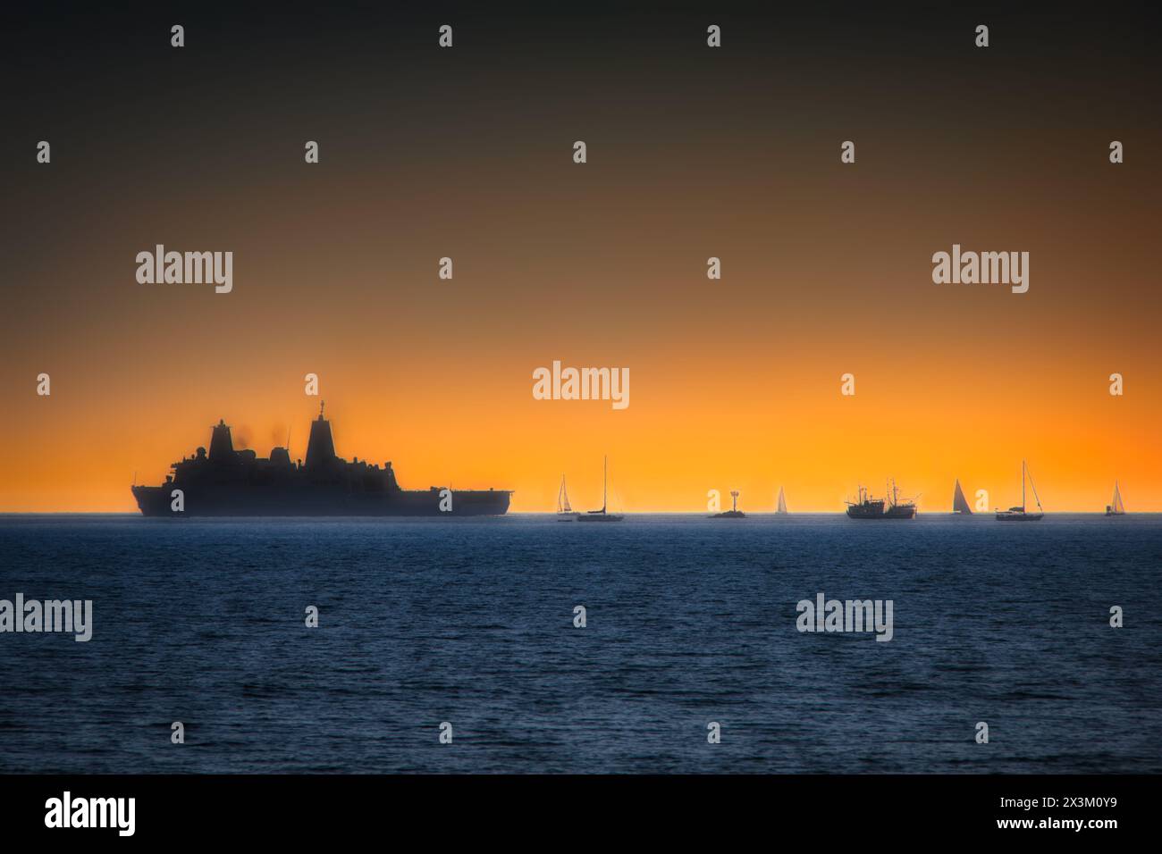 Un navire de l'US Navy passe des voiliers à l'horizon et juste au large de la côte de Coronado, en Californie. Banque D'Images