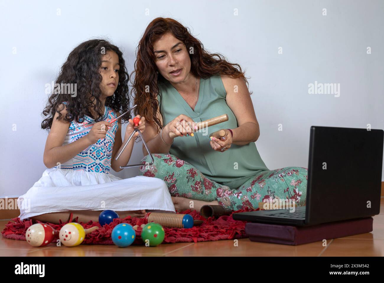 Maman et fille latino-américaines donnant des leçons de musique virtuelle avec des instruments de percussion Banque D'Images