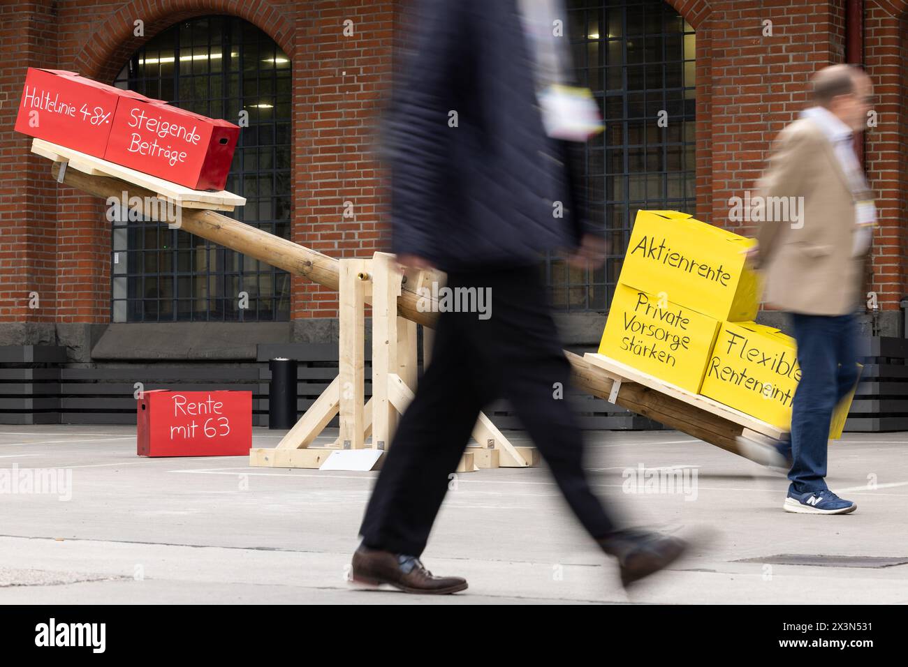 Berlin, Allemagne. 28 avril 2024. Les gens marchent devant une balançoire avec des boîtes en carton lors de la conférence du parti fédéral FDP à Berlin. Les encadrés rouges indiquent "ligne stop de 48 %", "augmentation des cotisations", "pension à 63 ans" et les encadrés jaunes disent "pension par actions", "renforcement des régimes de pension privés" et "retraite flexible". Crédit : Hannes P. Albert/dpa/Alamy Live News Banque D'Images