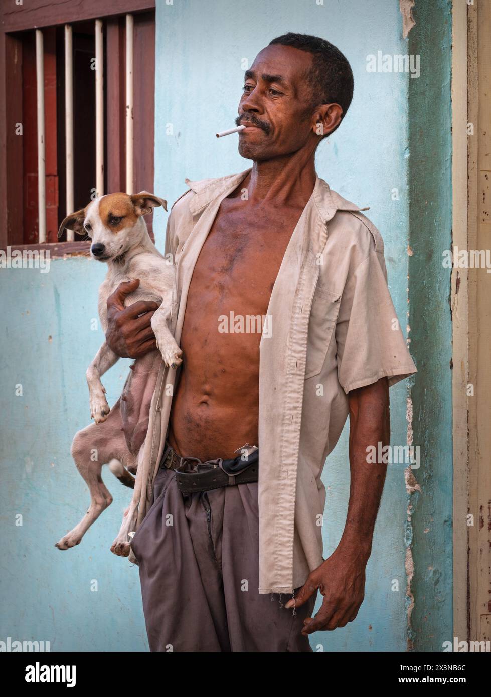 Homme fumant et tenant fièrement son chien posant pour une photographie dans les ruelles de la vieille ville, Trinidad, Cuba. Banque D'Images
