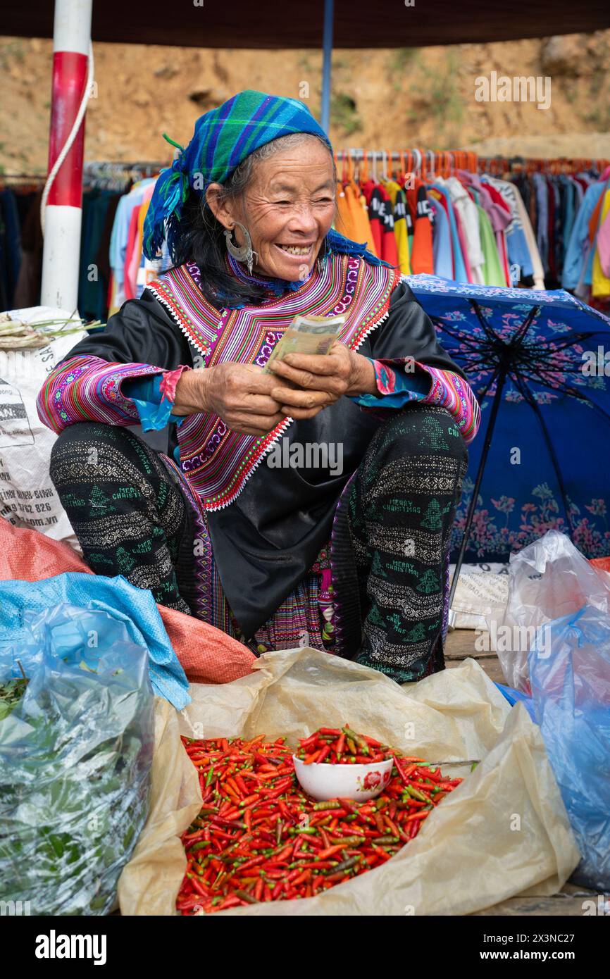 Femme hmong de fleur vendant des piments au marché de Can Cau dans la province de Lao Cai, Vietnam Banque D'Images