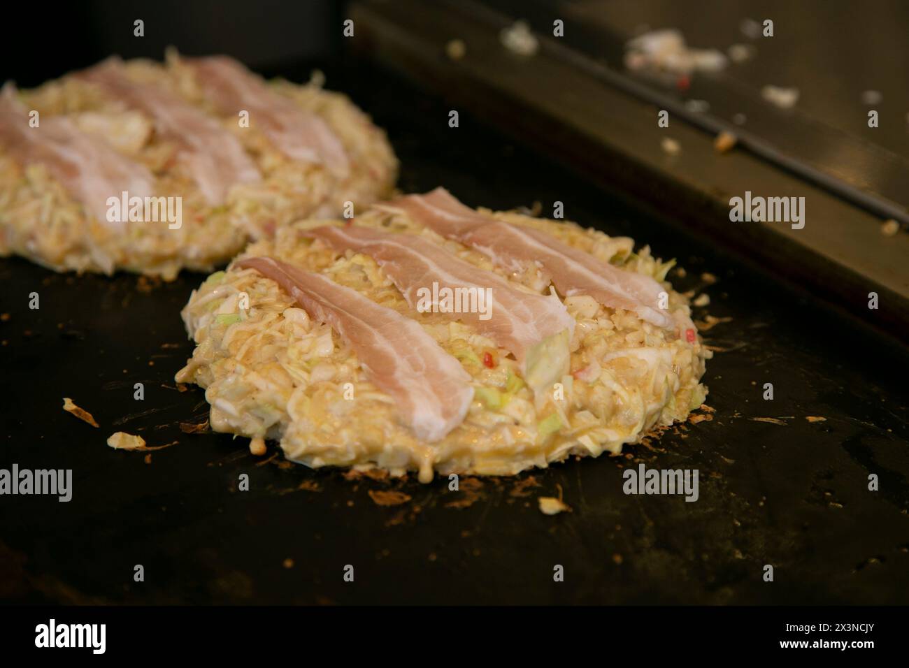 Okonomiyaki est une crêpe au chou japonais savoureuse « grillée comme vous l’aimez » avec votre choix de protéines et de condiments et garnitures savoureux. Banque D'Images