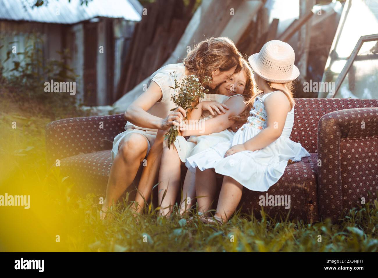 Jeune maman avec ses deux filles assis sur le canapé à l'extérieur. Fête des mères Banque D'Images