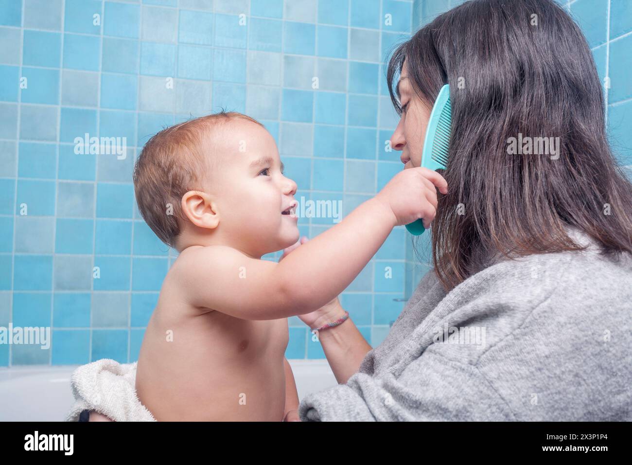 fils jouant à peigner les cheveux de sa mère après la douche Banque D'Images