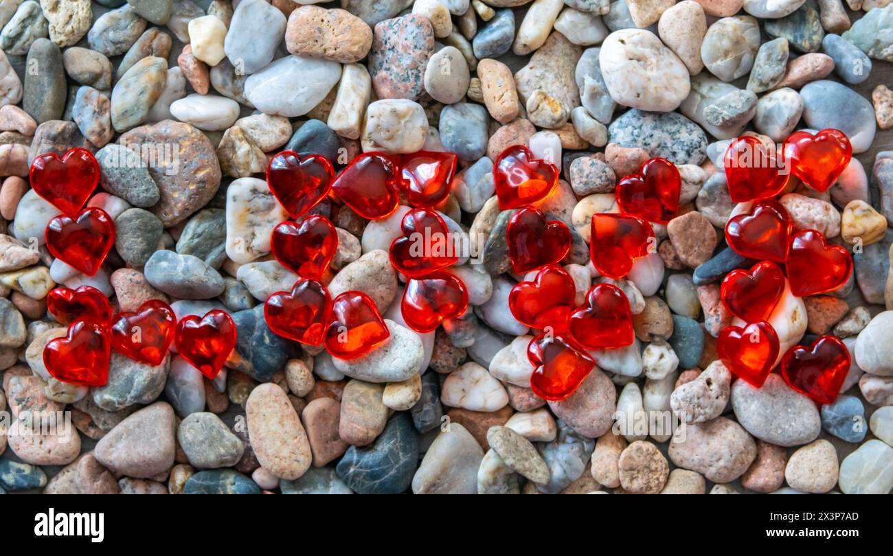 Mot amour des coeurs de verre rouge lumineux sur d'autres pierres près de la rivière. Banque D'Images