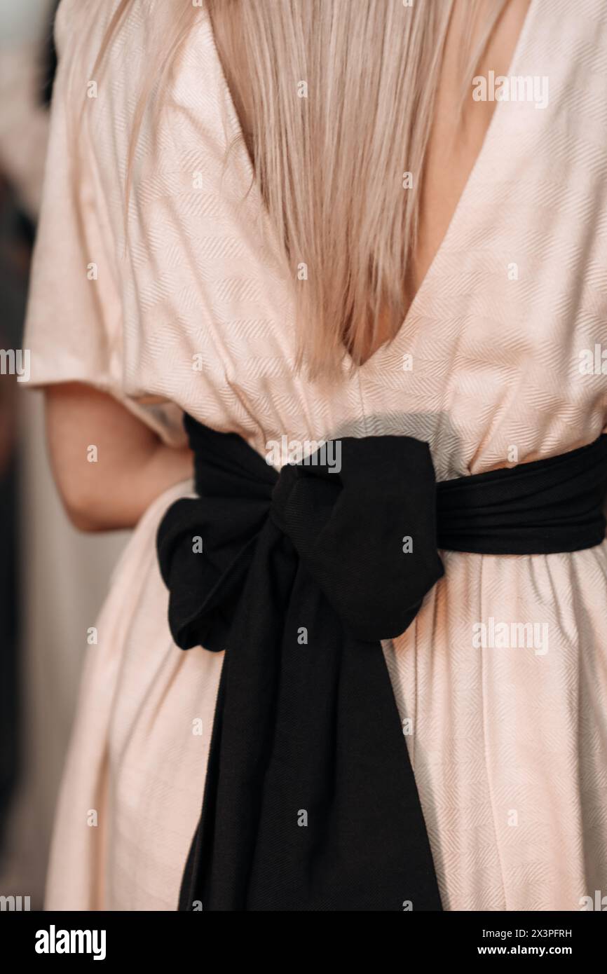 Beige élégant détails de mode féminine robe d'été printemps avec grand noeud noir à l'arrière. Coulisses du défilé de mode Banque D'Images