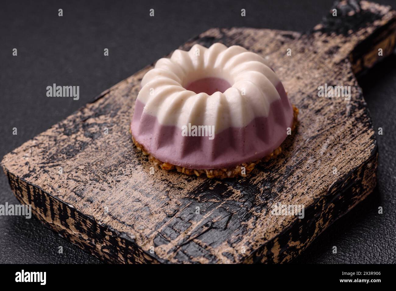 Délicieux cheesecake rond rose et blanc sans lactose, sans sucre, nutrition saine sur fond de béton foncé Banque D'Images