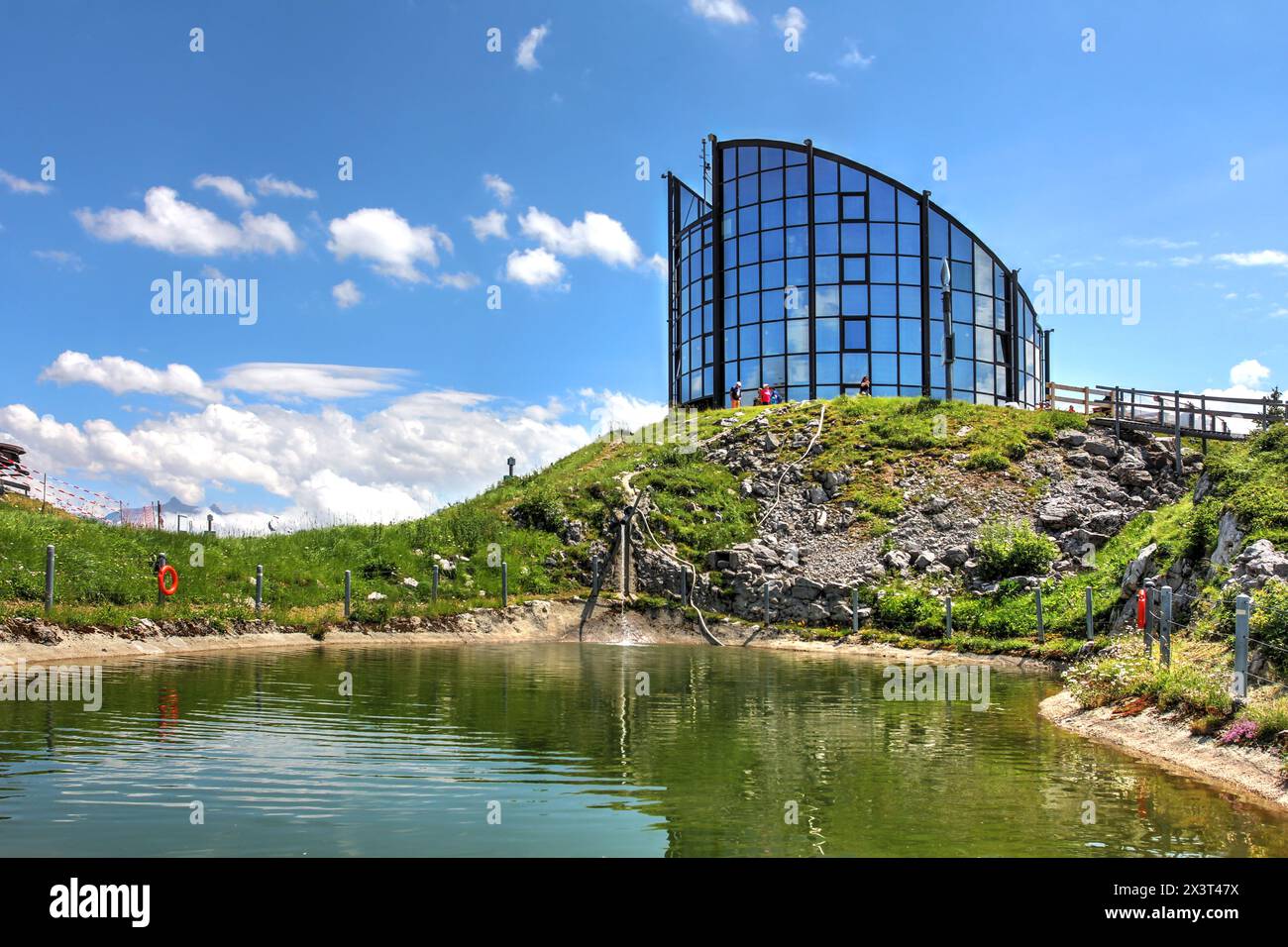 Kuklos - un restaurant tournant au sommet de la montagne sur la Berneuse (2048m) au-dessus de Leysin, Suisse reflétant dans le lac Yaka en été. Banque D'Images