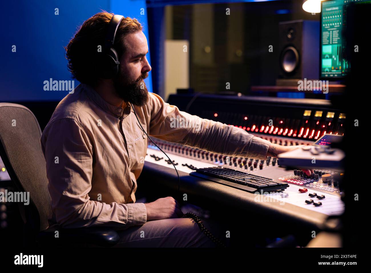 Producteur de mixage écoutant ses enregistrements audio et éditant des pistes en post-production, travaillant avec des équipements techniques et une console de mixage. Expert intégrant des sons amplificateurs à l'aide de faders motorisés. Banque D'Images