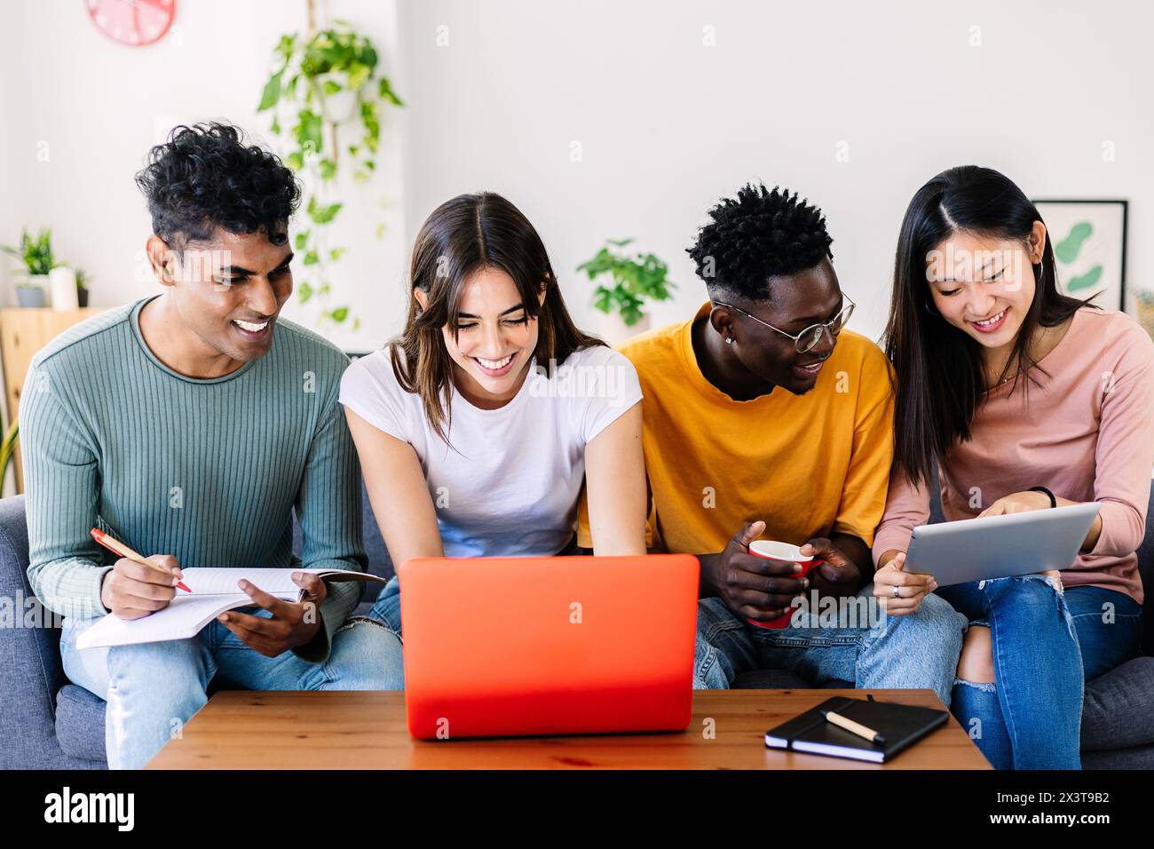 Jeune groupe d'étudiants divers étudiant ensemble à l'aide d'un ordinateur portable à la maison Banque D'Images