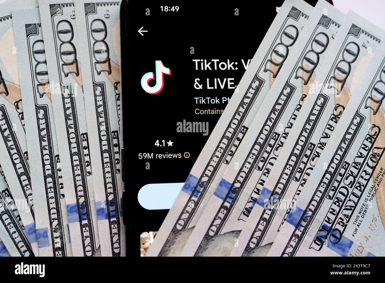 Application TikTok vu sur l'écran du smartphone qui est placé sur des dollars américains. Stafford, Royaume-Uni, 28 avril 2024 Banque D'Images
