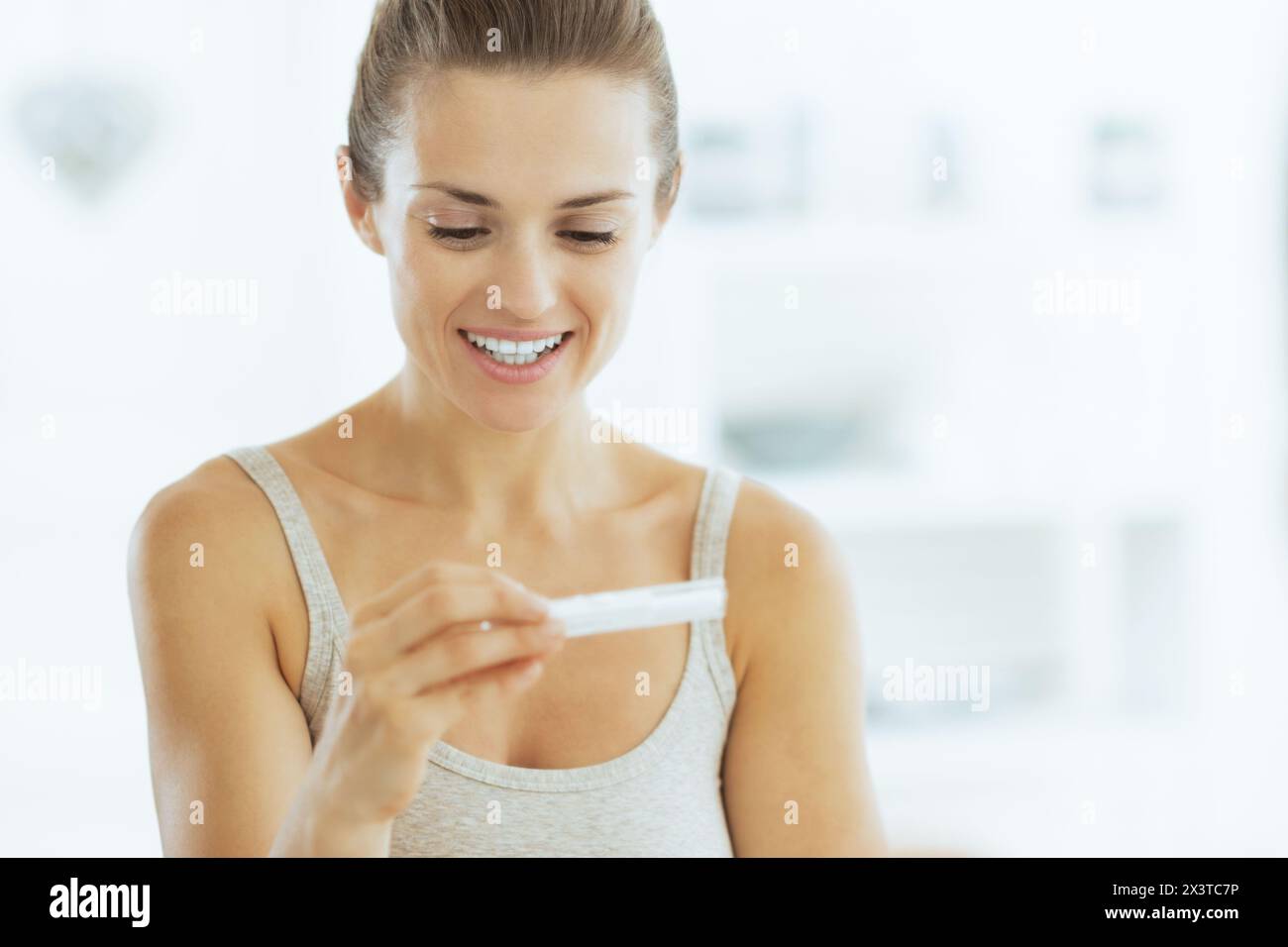 Happy young woman looking sur test de grossesse dans la salle de bains Banque D'Images