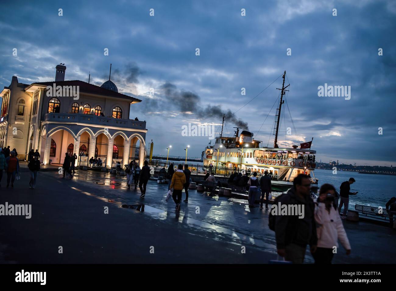 Istanbul, Turquie. 28 avril 2024. Les gens ont vu marcher sur la plage avec le ferry des lignes de la ville partant de l'embarcadère de Kadikoy au coucher du soleil. Crédit : SOPA images Limited/Alamy Live News Banque D'Images