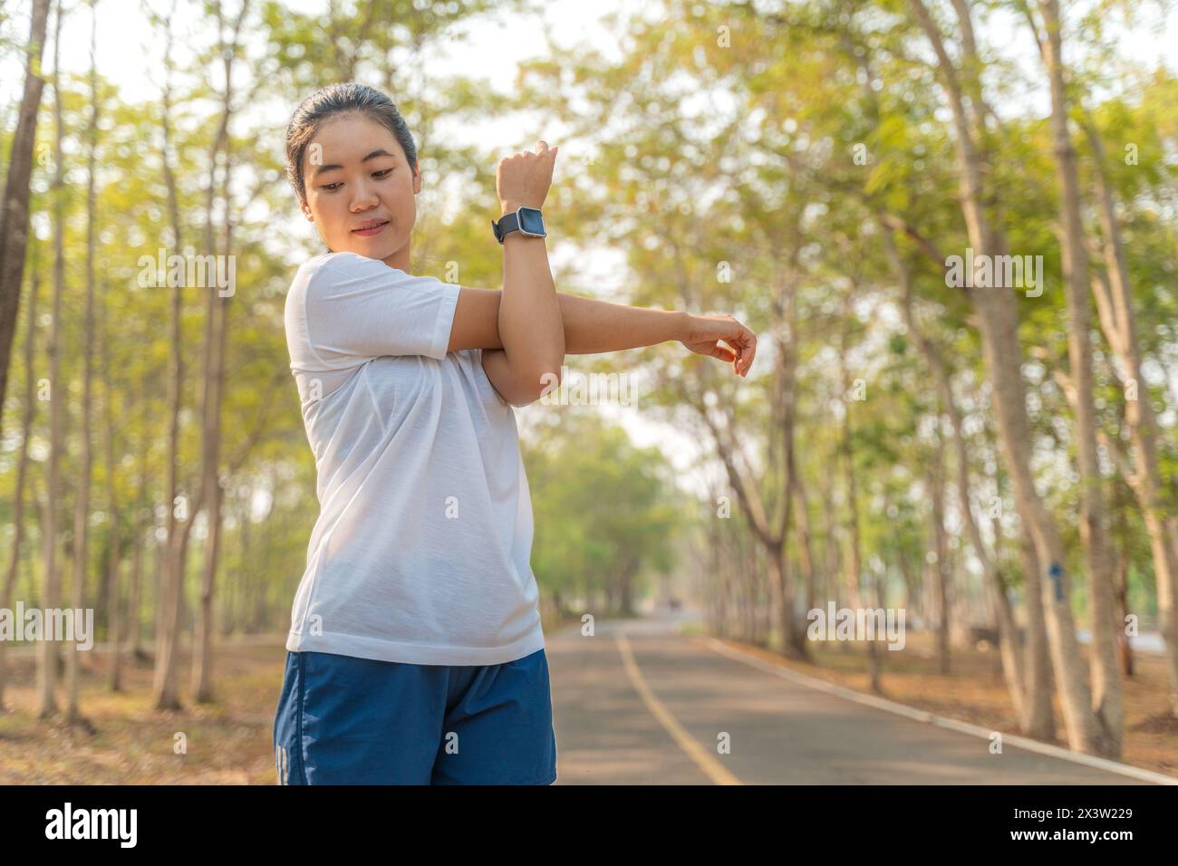 Jeune coureuse étirant ses bras et ses jambes avant de commencer sa course matinale dans un parc de course local Banque D'Images