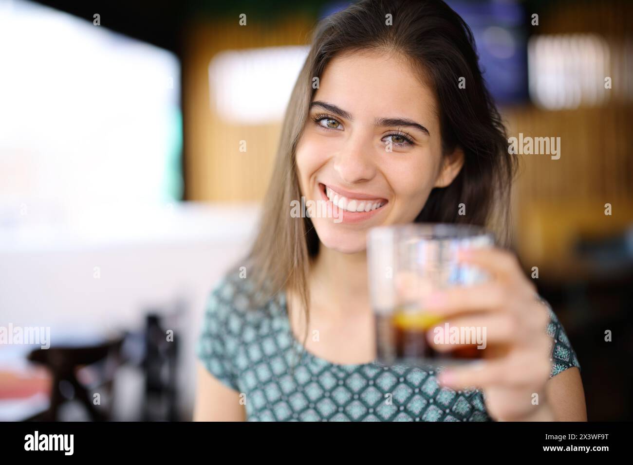 Portrait d'une femme heureuse vous offrant du soda dans un restaurant Banque D'Images